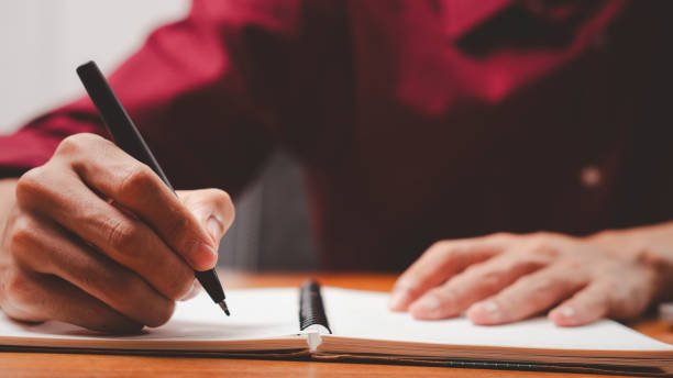 istock Male hand taking notes on the notepad. businessman working at work table, checklist writing planning investigate enthusiastic concept. focus on man hand holding pen, putting signature at official paper 2170390985