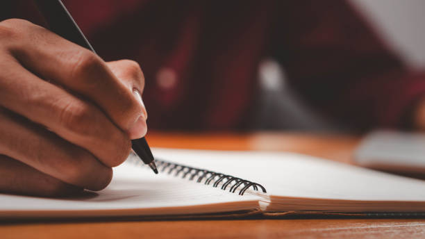 istock Male hand taking notes on the notepad. businessman working at work table, checklist writing planning investigate enthusiastic concept. focus on man hand holding pen, putting signature at official paper 2170390993