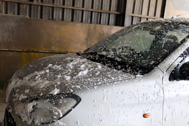 A car being washed with foam in an automatic car wash facility during the day
