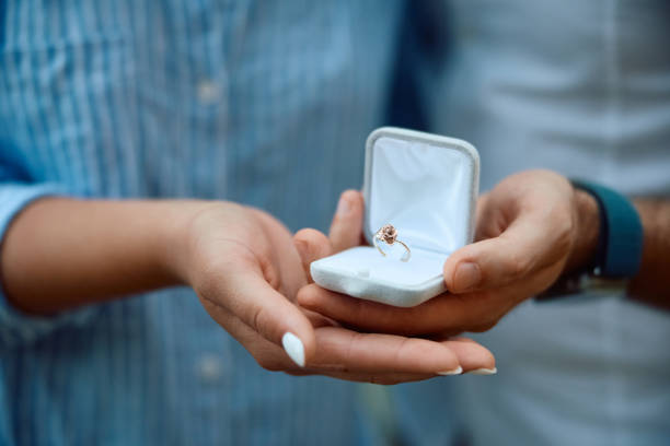 Close up of engaged couple with ring in jewelry box.