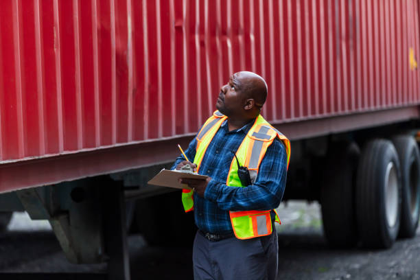 istock African-American man examining semi-trailer, writes on clipboard 2170405792