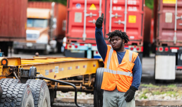 istock Man guiding tractor backing up to attach to semi-trailer 2170405802