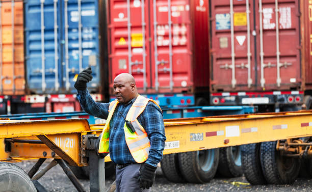 istock Man guides tractor, backing up to attach to semi-trailer 2170405814