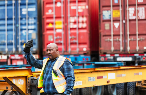 istock Man guides tractor, backing up to attach to semi-trailer 2170405815