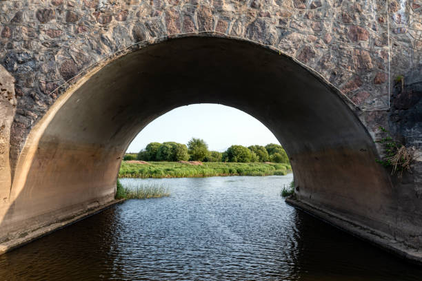 Stone bridge crossing river with flowing water underneath. Kandava, Latvia