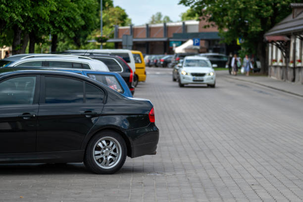 A black car parked on a city street with other cars. Shallow depth of feld