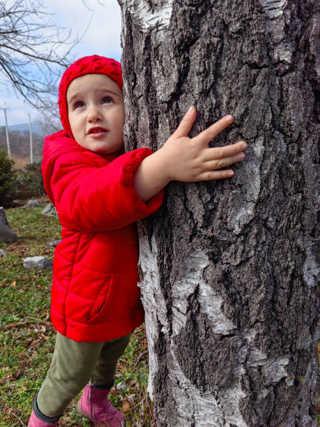 istock Child in Red Hugging Tree in Park in Winter. Nature Lover. 2170435465