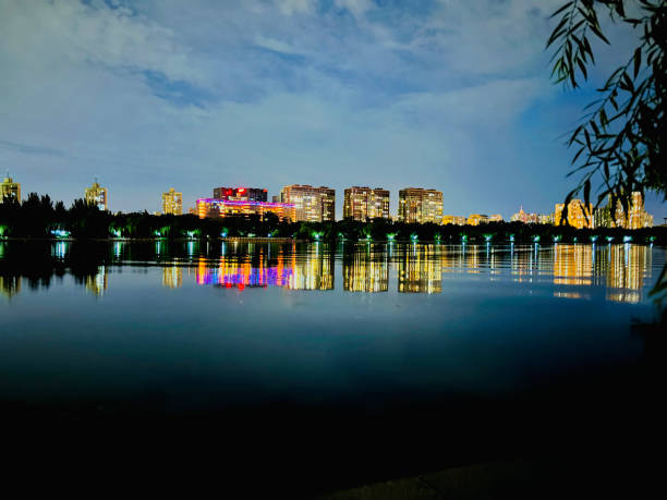 This striking image captures the serene reflection of evening building shadows in a calm lake. The interplay of architecture and water creates a visually stunning and tranquil urban landscape.