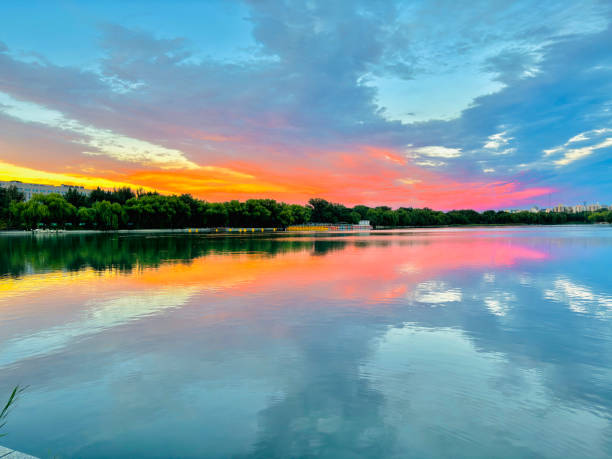 This breathtaking image captures a vivid sunset with a striking red sky reflecting over calm lake waters. The serene atmosphere perfectly blends the beauty of the sky with the peacefulness of nature.