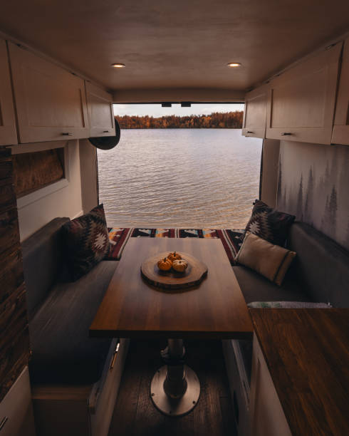 istock Vanlife Interior View Through Open Doors. Decorated with Mini Pumpkins Autumn Fall Foliage. Lake and Colorful Trees in Background. Camper Van 2170440823