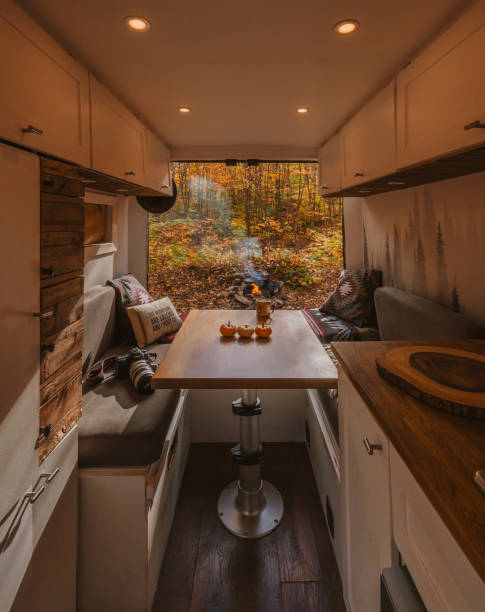Autumn Vanlife Digital Nomad Travel Camping. Camera, Coffee Cup, Decorated with Mini Pumpkins. Fall Foliage Doors Open, Campfire Burning. Camper