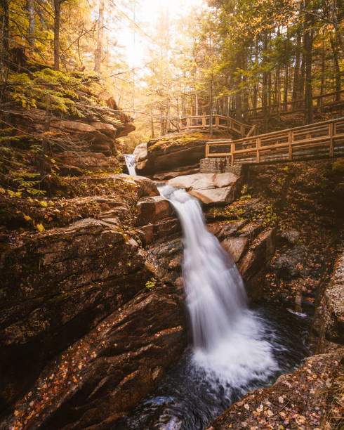 istock Autumn Fall Foliage Waterfall Sabbaday Falls New Hampshire White Mountain National Forest. Smooth Water Cascading Rocky Edge Forest Trail Wooden Bridge 2170441029