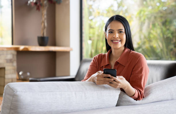 istock Woman at home using her cell phone while sitting on the sofa 2170445980