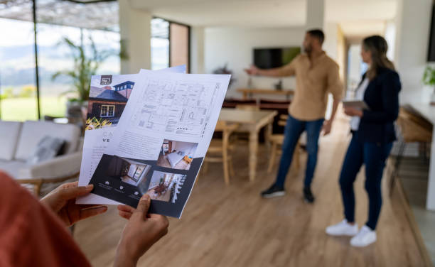 istock Client looking at a house brochure at a real estate showing 2170446117