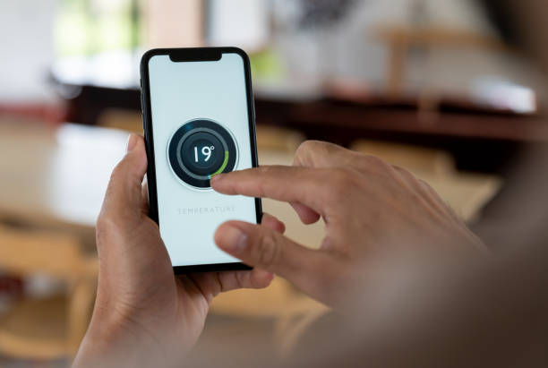 istock Man at home controlling his smart thermostat using a mobile app 2170446124