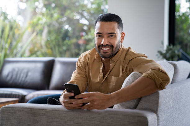 istock Man sitting on the sofa at home while texting on his cell phone 2170446143