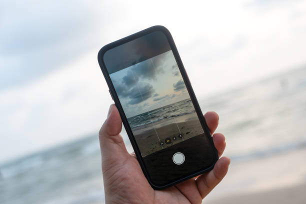 Man taking a photo with the mobile phone at the beach during sunset