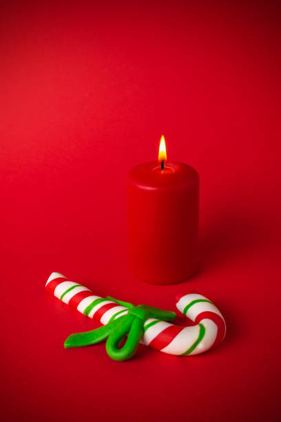 Red Candle with Candy Cane on Red Background: Festive Christmas Decoration