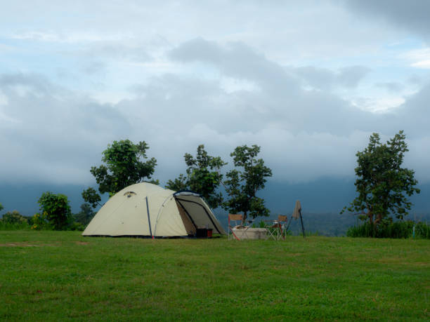 istock Cream Dome tent pitched on grassy field, mountainside grass field with a few trees in background. Some clouds in sky. Holiday activities 2170451015
