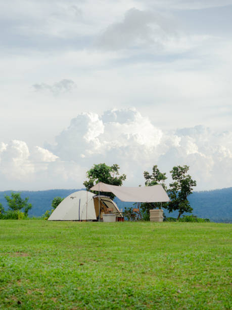 istock Cream Dome tent pitched on grassy field, mountainside grass field with a few trees in background. Some clouds in sky. Holiday activities 2170451018