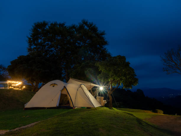 istock Atmosphere at night very good. Cream Dome tent pitched on grassy field, mountainside grass field with a few trees in background. Some clouds in sky. Holiday activities 2170451027