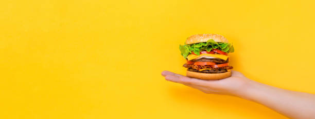 istock Hand holding hamburger on yellow isolated background 2170461634