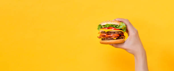 istock Hand holding cheeseburger on yellow isolated background 2170461643