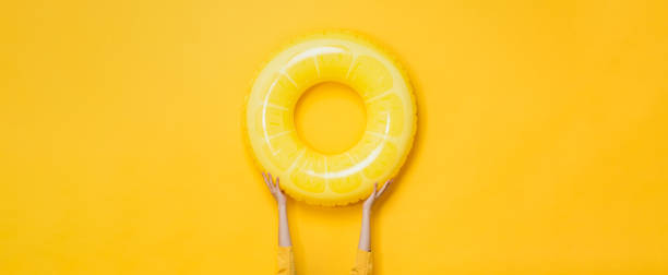 istock Yellow summer background with hands holding swim ring 2170461663