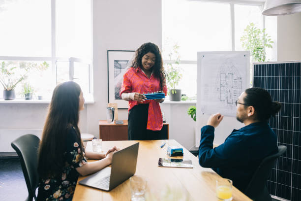 istock Team members brainstorm around a table with blueprints and a solar panel, focusing on renewable energy solutions 2170465645