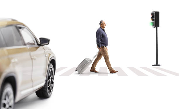 istock Mature man walking and pulling a suitcase at a pedestrian crossing 2170469930