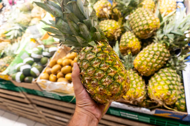 istock A person is holding a pineapple in a grocery store 2170471445