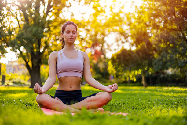 istock Young Woman Meditating Outdoors in Sunlit Park Setting 2170474834
