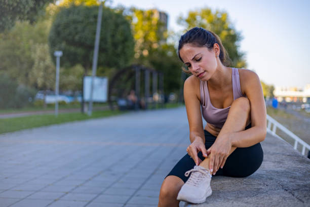 istock Woman Sitting on Path Holding Ankle in an Outdoor Setting 2170474876