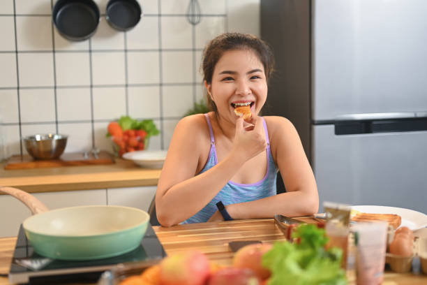istock Smiling young woman having breakfast at dining table 2170475034