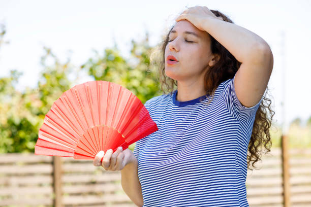 istock Young woman using handfan at park in a warm summer day 2170476201