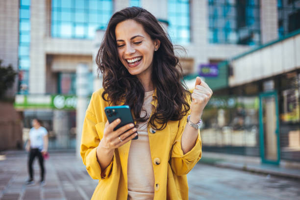 istock Happy Woman Celebrating Success While Using Smartphone Outdoors 2170478466