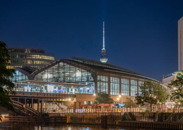 Germany, Berlin, Central Berlin, Station, Friedrichstrasse, August 29, 2024 - Illuminated Friedrichstrasse train station and communications tower at night