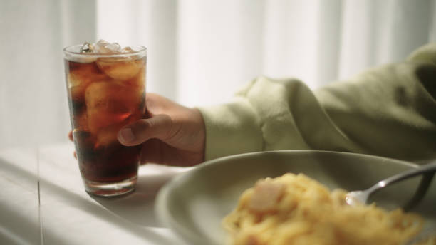 Cola in glass near blurred burger and french fries on black background