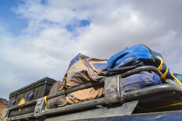 Car with a luggage cage placed on the roof where several suitcases and metal boxes are placed to store food and material for any unforeseen event during the trip.