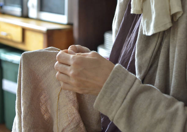 istock Hands sewing fabric indoors in natural light setting 2170494524