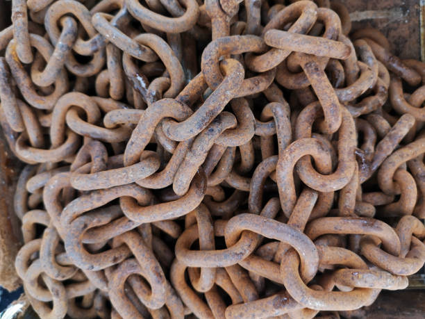 Pile of old rusty chains is laying on the ground, creating an interesting industrial background