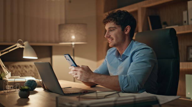 istock Night worker reading message on smartphone sitting office desk close up. 2170498510