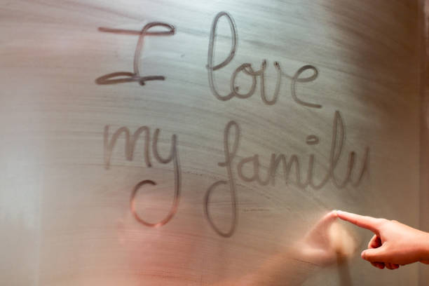 Hand of a person who has written a message on the four-way mirror of a bathroom that is full of mist.