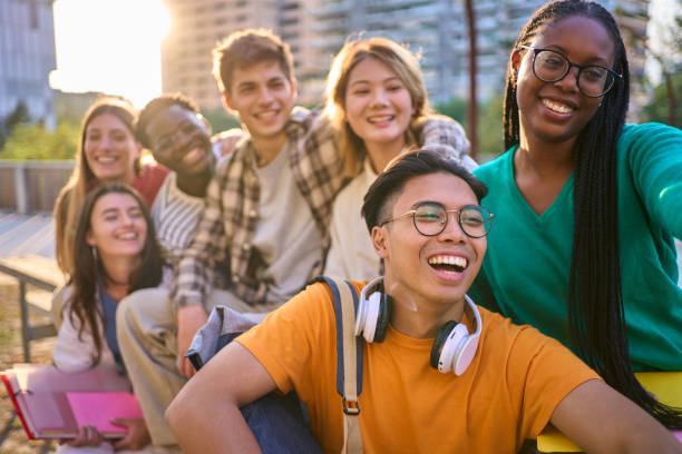istock Happy multiracial classmates university students posing sitting together taking selfie photo outdoor 2170499519