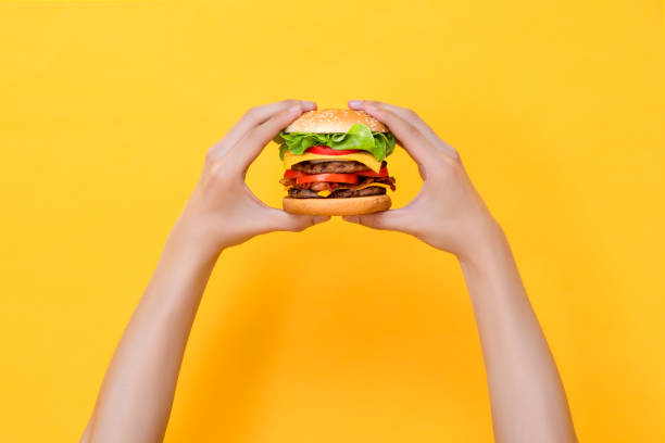 istock Hands holding hamburger on yellow isolated background 2170500780