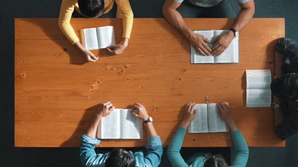 istock Top down view of smart prayer reading bible book while prays to god. Symposium. 2170508396