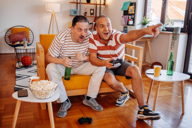 istock Middle age men having fun at home playing video games together while sitting on sofa 2170512398