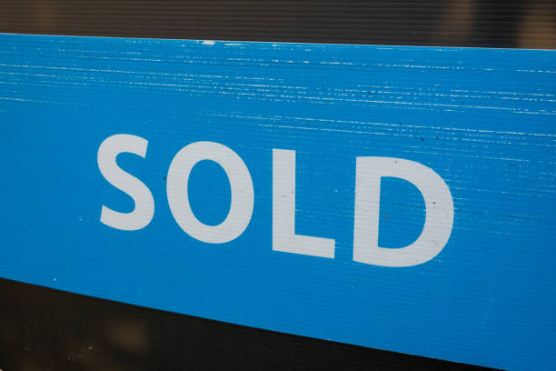 Smiling worker holding sold sign outdoors