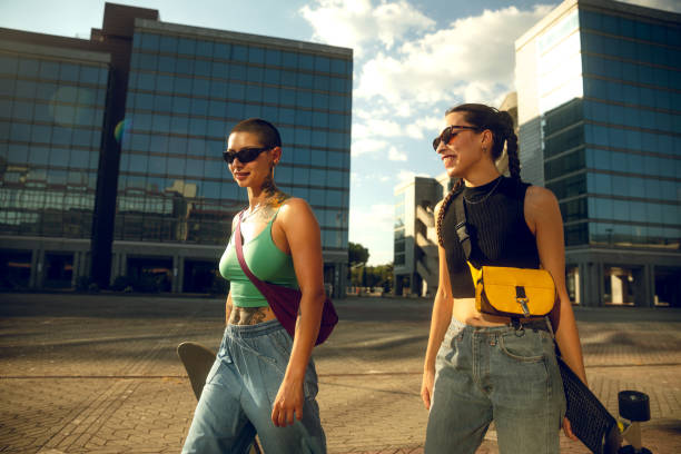 Two young woman walking with skateboard