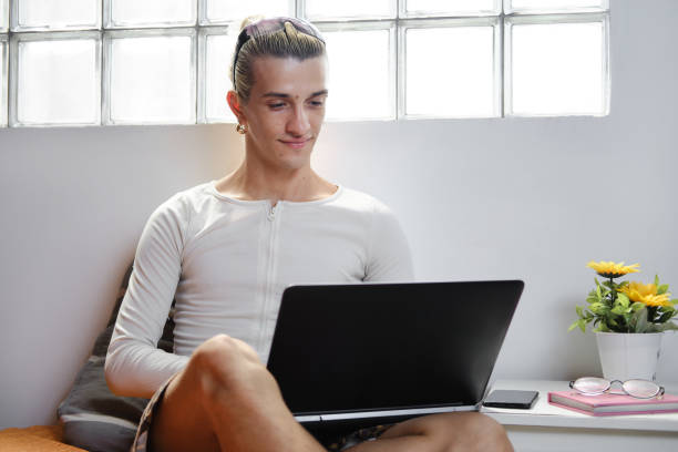 front view portrait of a carefree Latino smiling focused and using a portable information device to work or telecommuting from his apartment indoors in Barcelona
